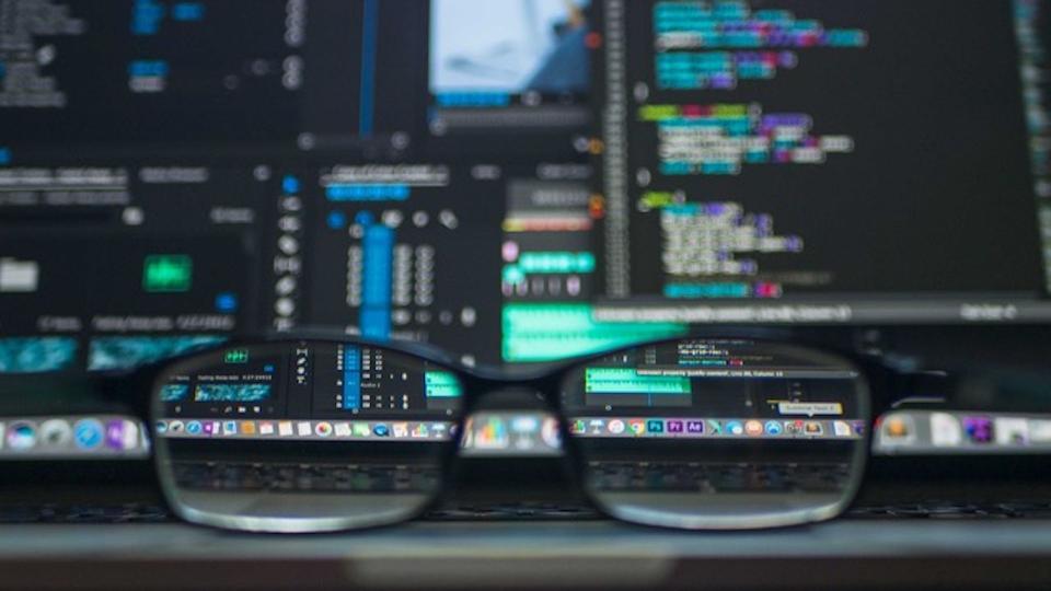 Brille mit Computerbildschirmen im Hintergrund