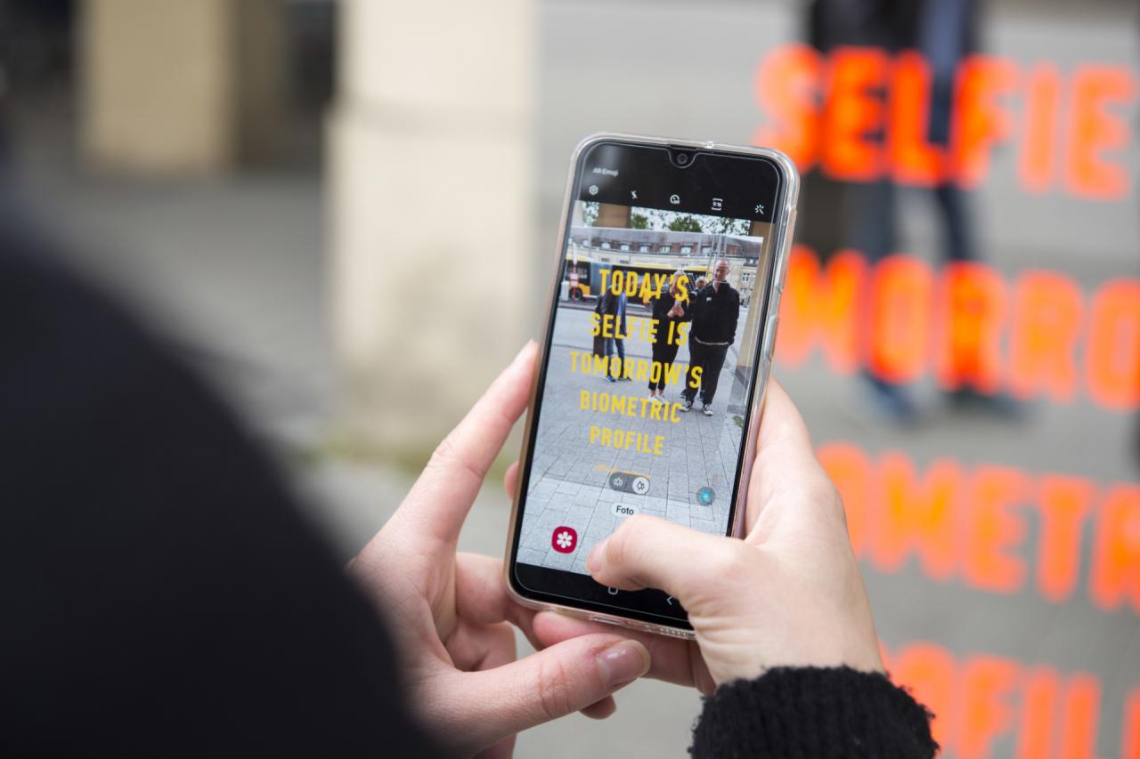 Vor der Spiegelinstallation ist ein Handybildschirm zu sehen mit dem Schriftzug: Todays Selfie Is Tomorrows Biometric Profile.